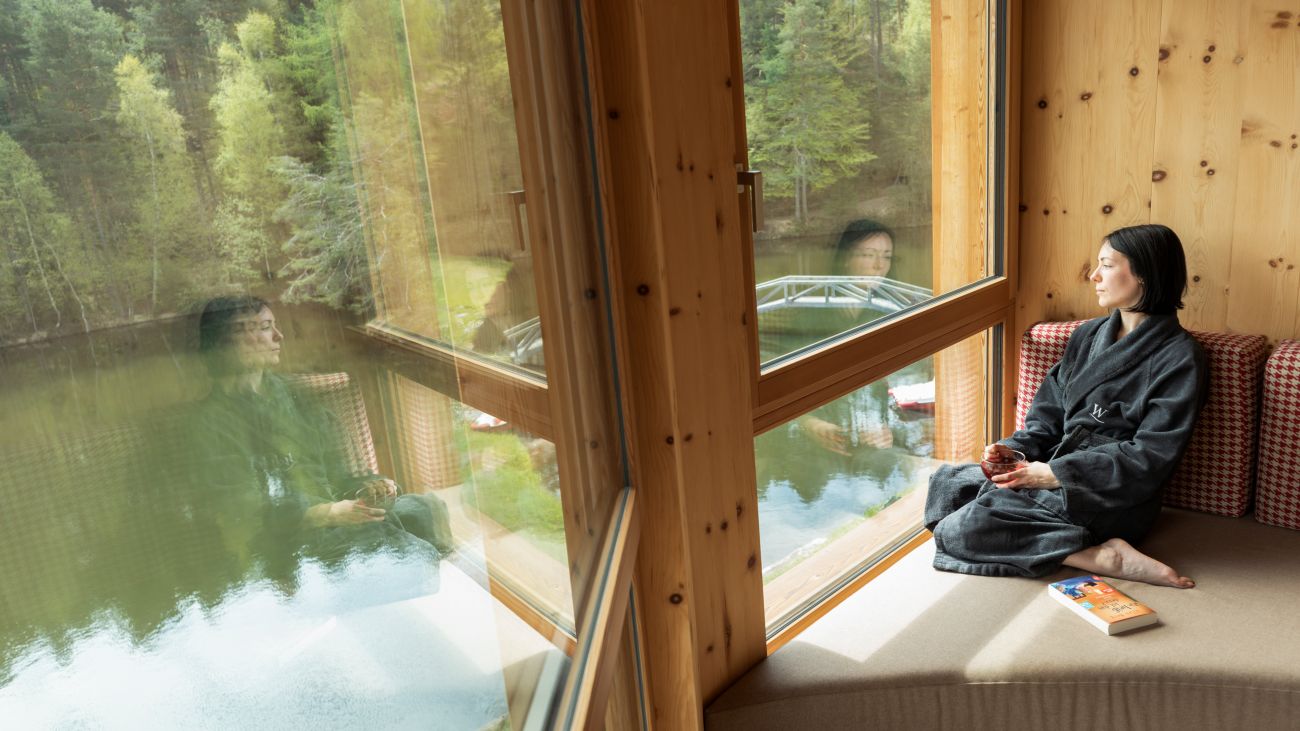 Woman in a sustainable hotel room enjoying the view of the lake in South Tyrol