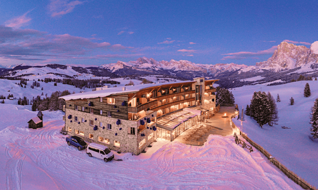 Sustainable ski-in ski-out hotel at dusk Dolomites panorama