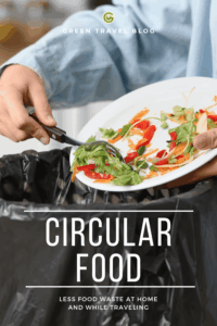In the foreground, a person is holding a white plate with colorful vegetable scraps, including lettuce leaves, bell peppers, and tomatoes. Using black tongs, the food scraps are being disposed of in a large black trash can. At the top of the image is the logo and the text ‘GREEN TRAVEL BLOG’. At the bottom, the text ‘CIRCULAR FOOD’ and ‘LESS FOOD WASTE AT HOME AND WHILE TRAVELING’ can be seen. The image addresses food cycles and the sustainable handling of food in hotels.